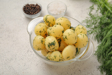 Bowl with boiled baby potatoes on light background