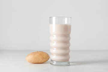 Glass of tasty potato milk on light background
