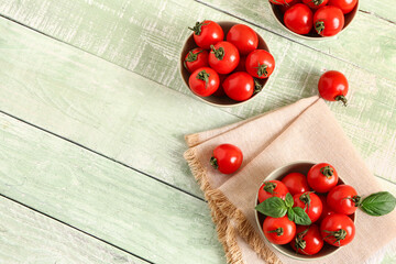 Bowls with fresh cherry tomatoes and basil on green wooden table