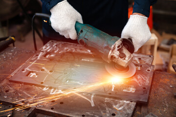 a worker man using grinding machine to clean rust from steel plate with light and flare