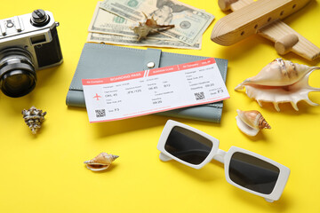 Wallet, ticket, sunglasses and seashells on yellow background