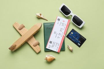 Composition with ticket, credit card, wooden plane and sunglasses on green background