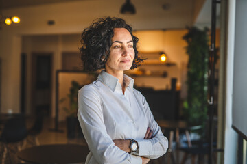 One woman mature caucasian female businesswoman entrepreneur stand at work or home real people copy space wear white shirt curly hair - Powered by Adobe