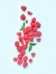 Many fresh raspberries and mint on blue background