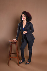 Young manager, elegant and beautiful, leaning on a wooden stool.