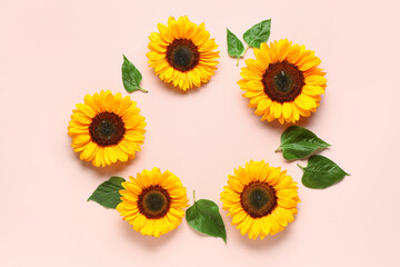 Frame made of beautiful sunflowers and leaves on pink background