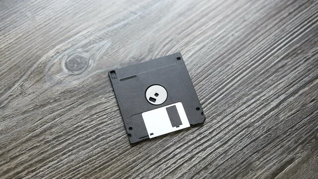 A man puts a floppy disk on the table. The diskette is on the table. Flexible magnetic disk.