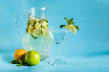 Homemade lemonade with lemon, mint and apple on a blue background