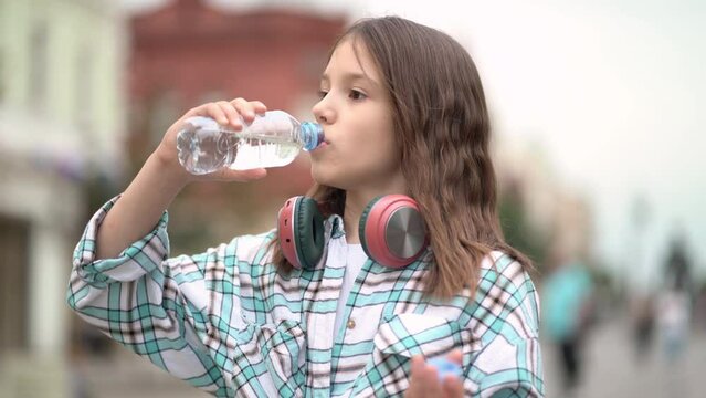 portrait girl drinking bottled water on the street.