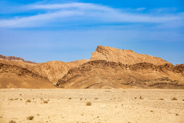Fototapeta na wymiar Landscape photography of Sahara desert, sand dunes and stones sunny day. View of expanses of desert hills with sand, vegetation and blue sky, Sahara, Tozeur city, Tunisia, Africa. Copy ad text space