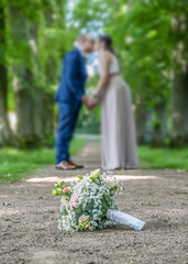 Wedding bouquet on foreground of a blurred kissing couple. Flowers and lovers - 623238167