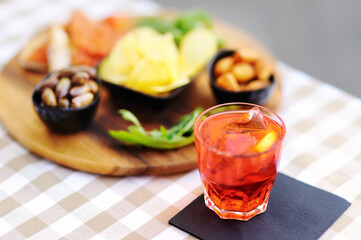 Italian aperitives/aperitif: glass of cocktail (sparkling wine with Aperol) and appetizer platter on the table