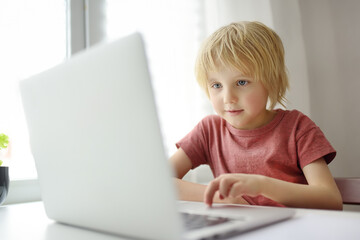 Schoolboy use computer app for study by laptop at home. Child and gadgets. Online education and distance learning for children