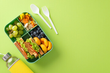 Wholesome snack arrangement for school. Top view featuring lunchbox with variety of fresh fruits,...