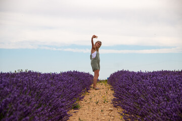 Blonde woman with mobile phone in hand enjoying her summer vacation in a blooming field of lavenders