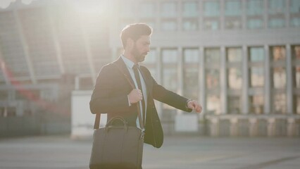 Employee looks at wristwatch and speeds up walk being late