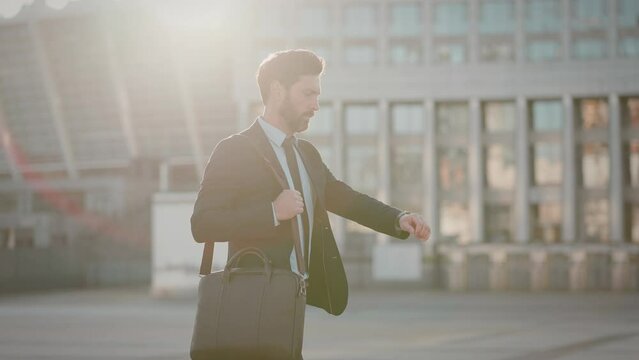 Employee looks at wristwatch and speeds up walk being late