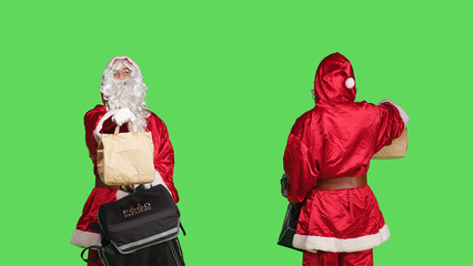 Joyful santa claus person deliver food in paper bag, carrying thermal backpack while he is wearing traditional holiday costume. Man in festive red and white suit, greenscreen backdrop.