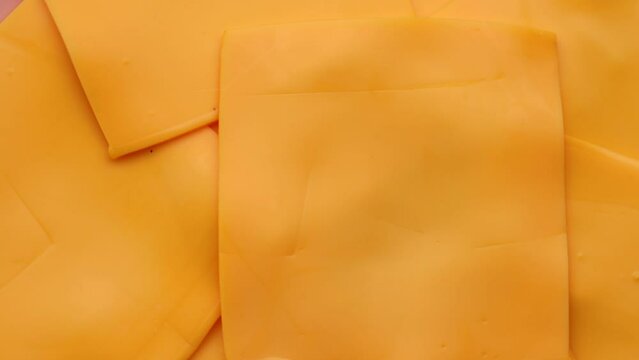 slices of yellow cheddar cheese, rotation in circle. Square slices of processed cheese for a burger, Turning. selective focus.