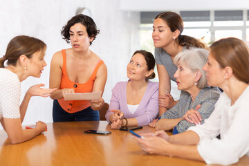 Fototapeta na wymiar Group of positive people of different ages sitting around table and communicating