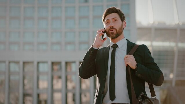Successful businessman speaks with client on phone by office