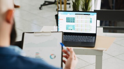 Fototapeta premium Startup consultant researching project using archived documents with analytics, working in business office. Company analyst looking at executive data papers, solving tasks at job. Handheld shot.