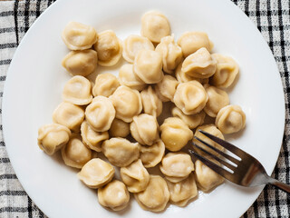 Big portion of Russian dumplings on a white plate. Tasty dinner. Classic west European dish.