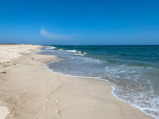 Footprints on an empty beach by the waters edge