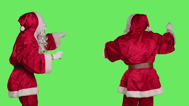 Saint nick musician conducting orchestra, choirmaster in costume accompany choir notes over greenscreen backdrop. Santa acting like musical director, musician singing in studio.