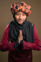 A young malay teenager girl wearing a traditional Negeri Sembilan costume on brown color background