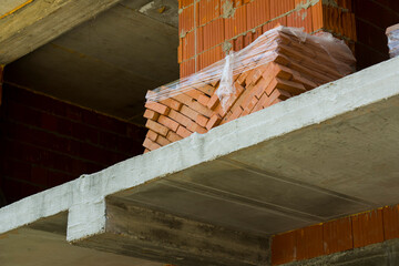 a stack of red bricks on a construction site. red ceramic bricks in a building under construction.