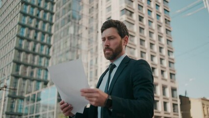 Bearded businessman looks at papers intently going to work