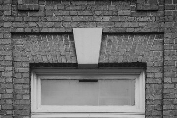 Old transom window and solid brick in monochrome