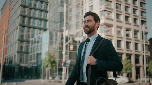 Smiling bearded man in business suit walks down city street