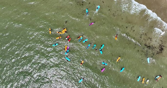 A beach with a surfing school practising on the waves by the shore 4k