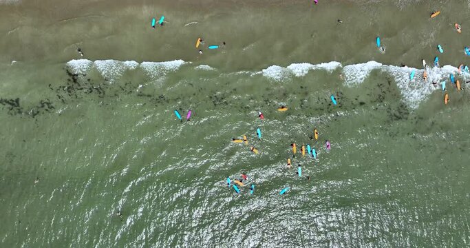 Surfers ride the waves on a beach with clear water 4k
