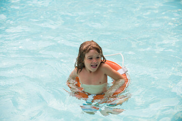 Kid swimming in pool. Summer holidays. Boy having fun at aquapark. Happy child with lifebuoy. Summer child.