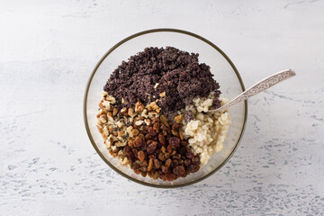 Barley with honey, raisins, nuts and poppy seeds in a glass bowl on a light blue background, top view. Cooking Christmas sochivo, a traditional Russian dish