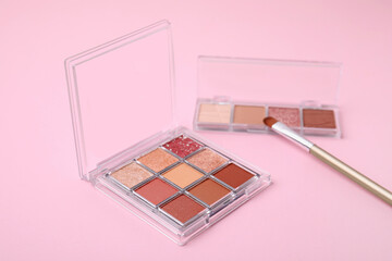 Beautiful eye shadow palettes and brush on pink background