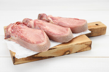 Raw beef tongue pieces on white wooden table, closeup