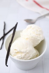 Delicious ice cream and vanilla pod on white table, closeup