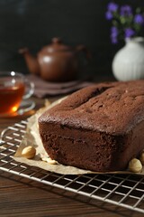 Fototapeta na wymiar Delicious chocolate sponge cake and nuts on wooden table, closeup