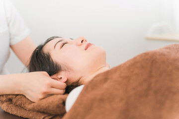 耳ツボマッサージの施術を受けるアジア人女性
