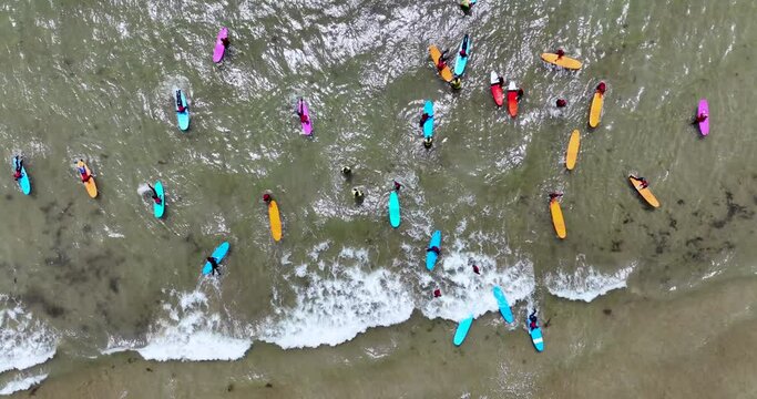 An overhead view of colourful surfboards, surfers gathered to ride 4k