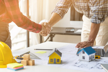 Engineer and contractor planning projects together at desk with blueprints.