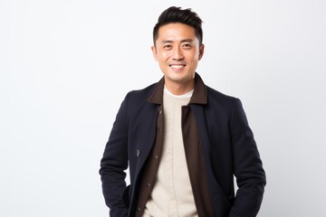 Young asian man standing on white background and smiling at camera.