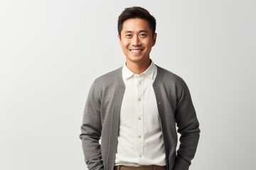 Portrait of a smiling young asian man standing against white background