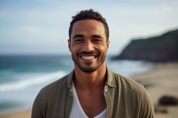 Portrait of handsome man smiling at camera at beach during sunny day