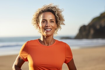 Portrait of smiling sporty woman with curly hair standing on beach