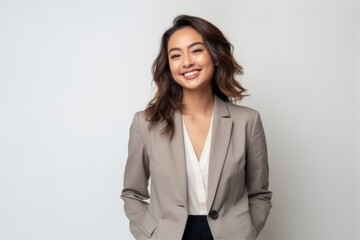 Portrait of happy young business woman smiling at camera on grey background